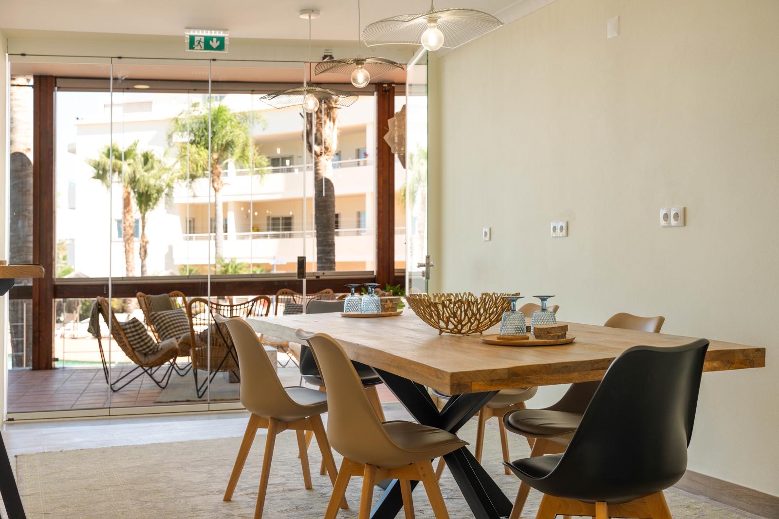 Bright meeting room with solid wood table opening onto the poolside terrace