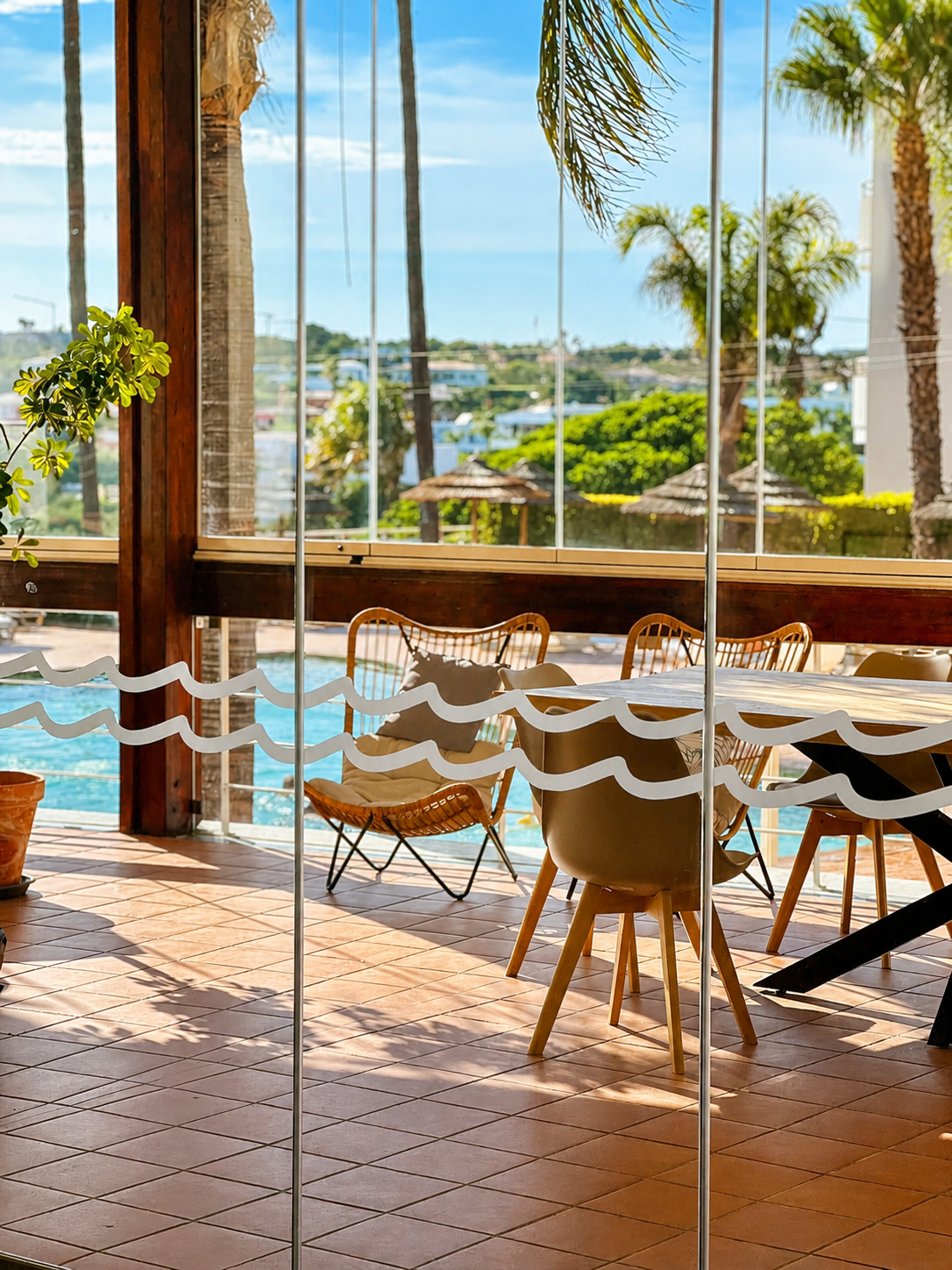 Pool terrace seen through the wave-etched glass of the lounge